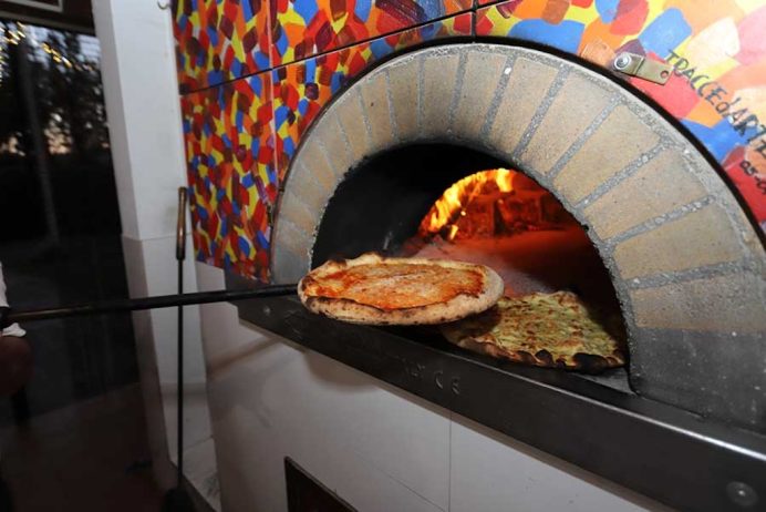 Picture of a pizza coming out of a wood-fired oven
