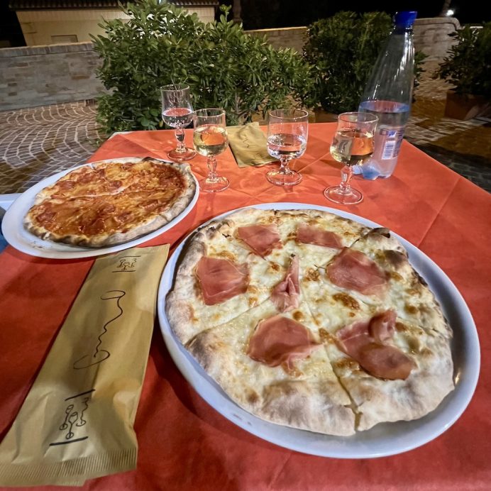 Photo of two thin crust pizzas on a table outside.